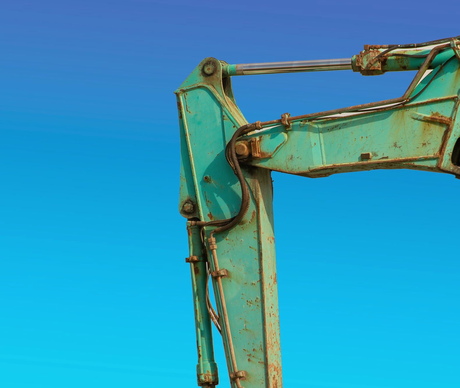 A boom arm with its hydraulic cylinder rod extended against a blue sky